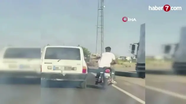 Şanlıurfa'da tehlikeli yolculuk: Motosiklet, otomobil kemerine tutunarak ilerledi
